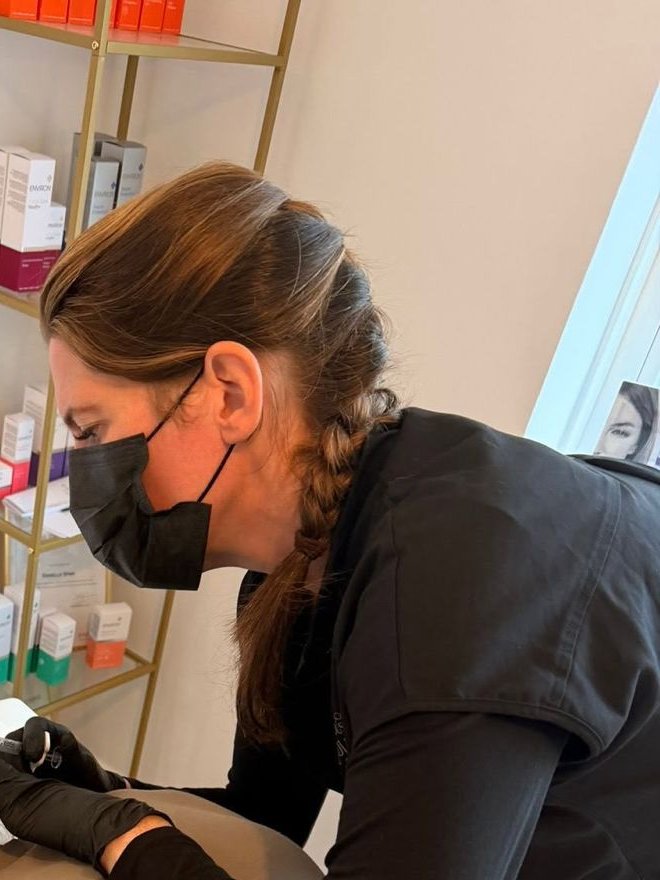 Danielle at work in the treatment room, with the Environ product shelf behind her