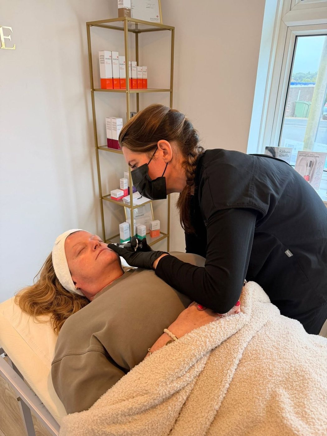 A facial in progress in the treatment room at The House of Radiance, with the Environ product shelf behind